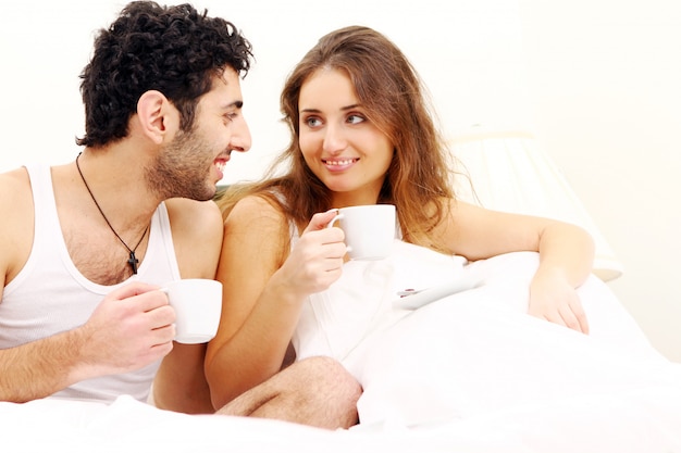 Pareja joven desayunando en la cama