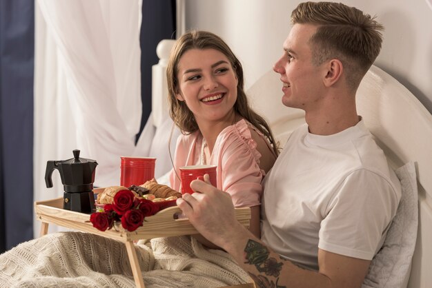 Pareja joven desayunando en la cama