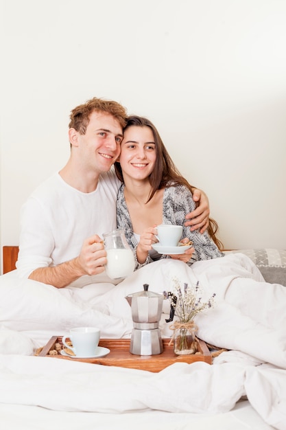 Foto gratuita pareja joven desayunando en la cama