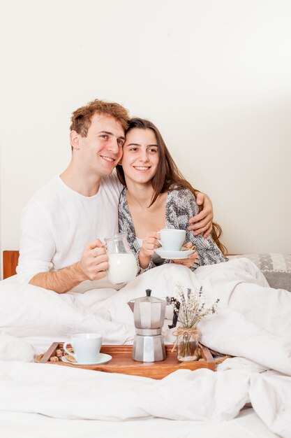 Pareja joven desayunando en la cama