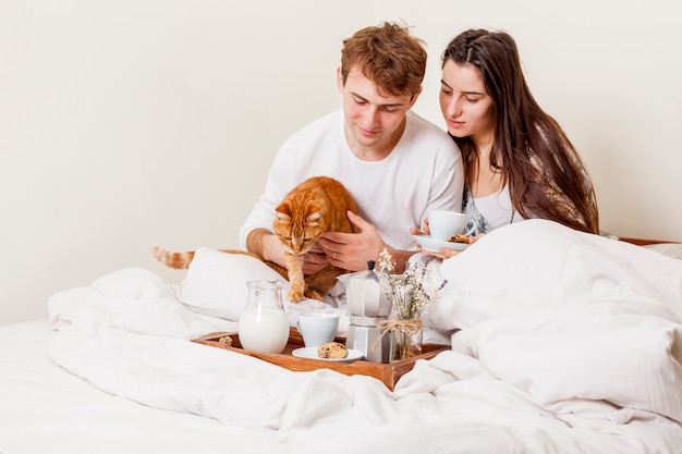 Pareja joven desayunando en la cama