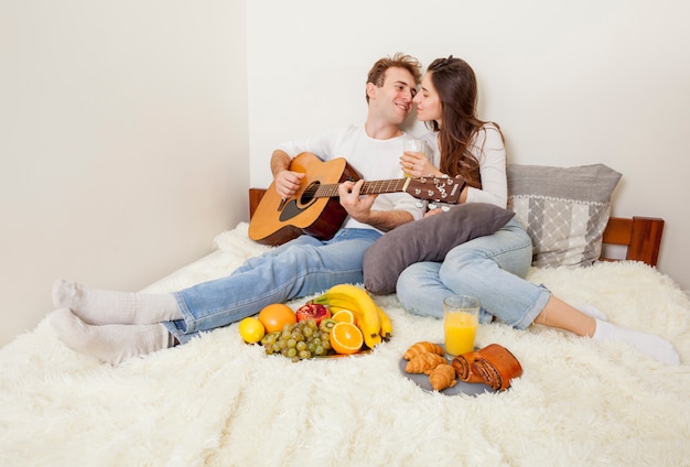 Pareja joven desayunando en la cama