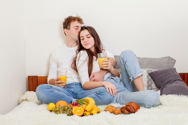 Foto gratuita pareja joven desayunando en la cama