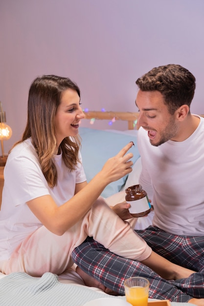 Pareja joven desayunando en la cama