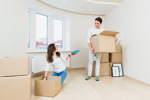 Pareja joven después de mudarse a una nueva casa, desempaquetando sus artículos.