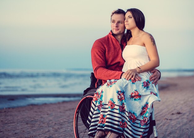 Pareja joven discapacitada descansando en una playa.