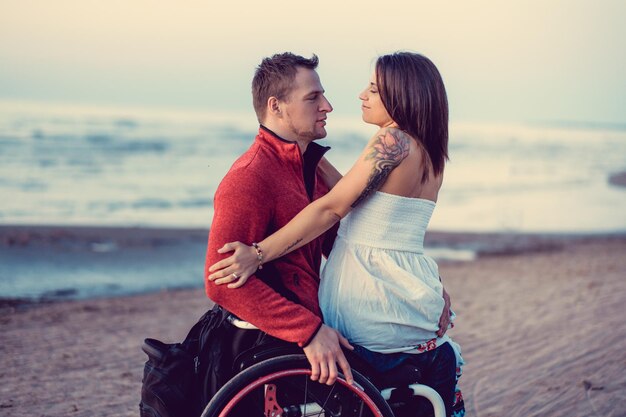 Pareja joven discapacitada descansando en una playa.