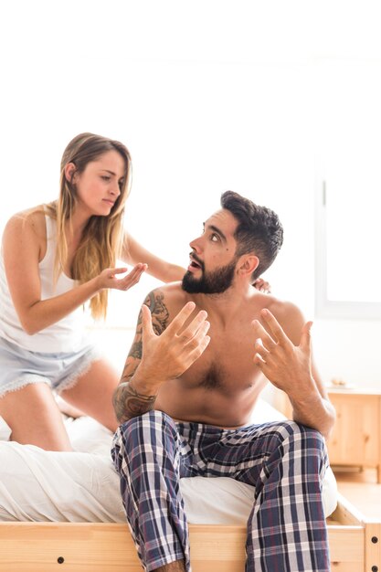 Pareja joven discutiendo en la cama en el dormitorio