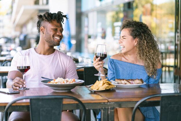 Pareja joven disfrutando y pasando un buen rato juntos mientras tienen una cita en un restaurante.