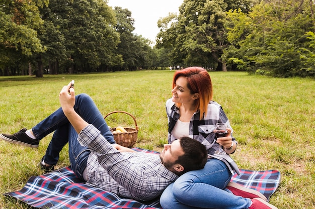 Pareja joven disfrutando en el picnic tomando selfie en teléfono móvil