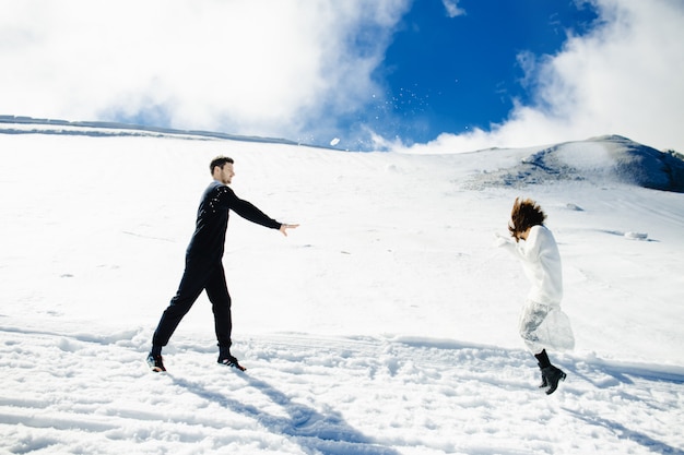 Pareja joven divertirse y jugar bolas de nieve