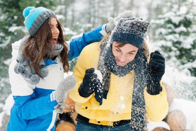 Pareja joven divertirse durante la pelea de bolas de nieve