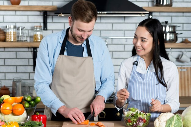 Pareja joven divirtiéndose mientras preparaba la comida en la cocina