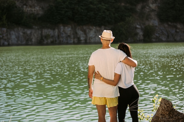 Pareja joven divirtiéndose en la orilla del río en un día soleado