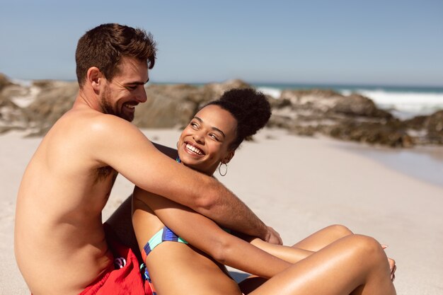 Pareja joven divirtiéndose en la playa bajo el sol