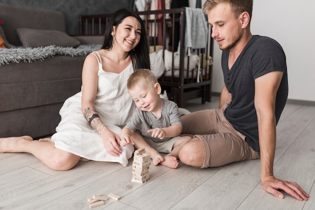 Pareja joven divirtiéndose con su pequeño hijo jugando con bloques de madera