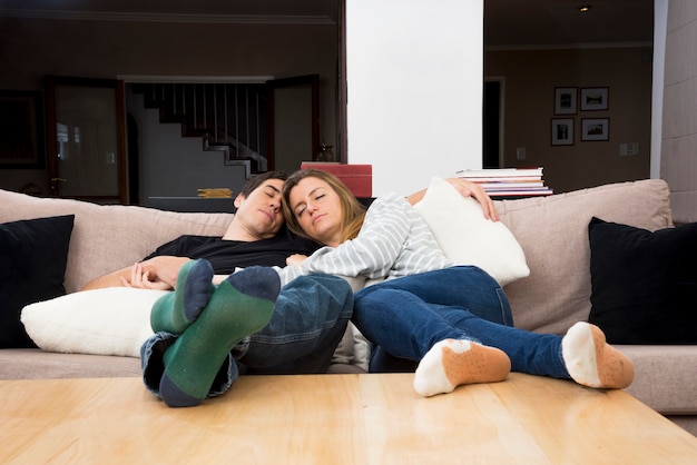 Pareja joven durmiendo juntos en el sofá en casa