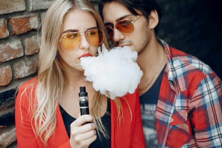 Foto gratuito una pareja joven y elegante con vape en una ciudad.