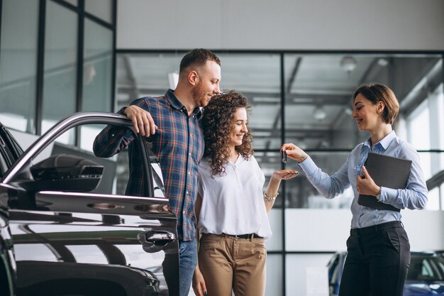 Pareja joven eligiendo un automóvil en una sala de exhibición de autos