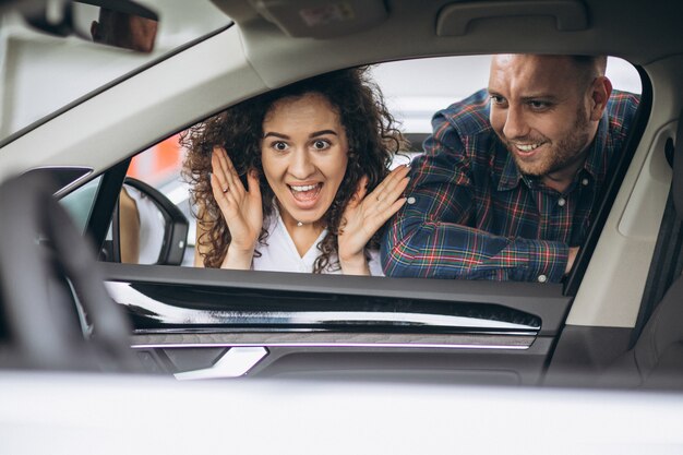 Pareja joven eligiendo un automóvil en una sala de exhibición de autos