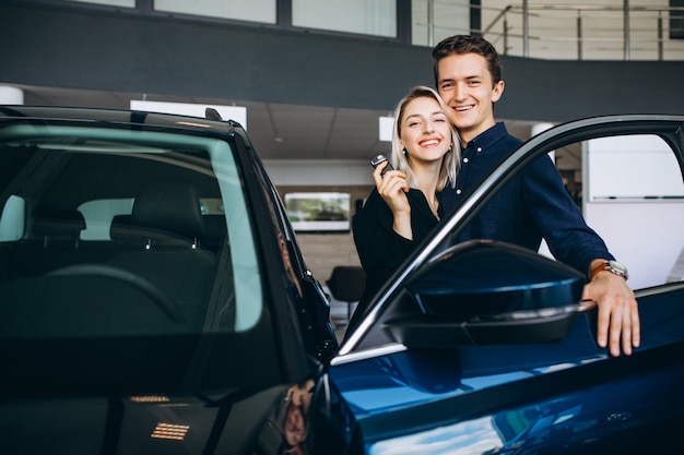 Pareja joven eligiendo un automóvil en una sala de exhibición de autos