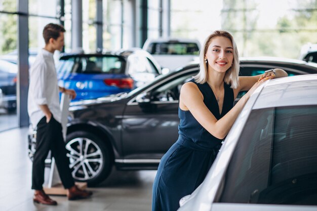 Pareja joven eligiendo un automóvil en una sala de exhibición de autos