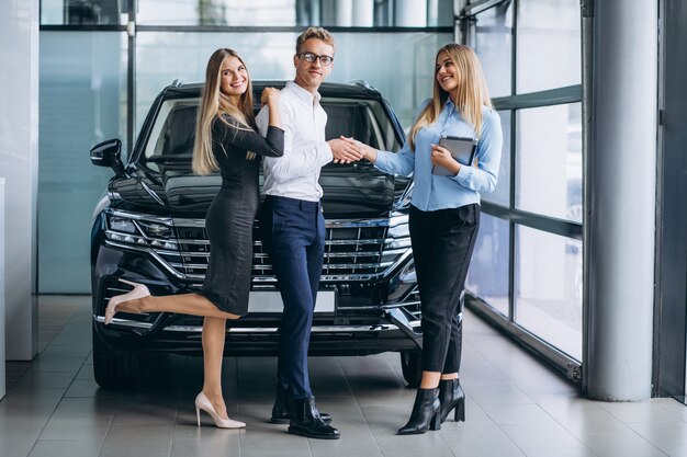 Pareja joven eligiendo un automóvil en una sala de exhibición de autos