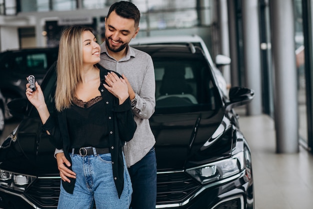 Pareja joven eligiendo un automóvil en una sala de exhibición de autos