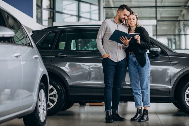 Pareja joven eligiendo un automóvil en una sala de exhibición de autos