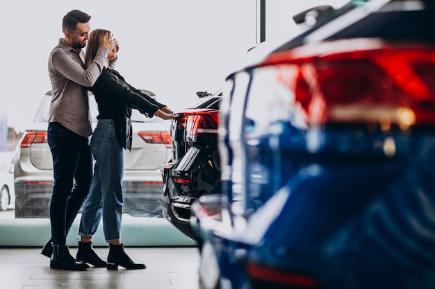 Pareja joven eligiendo un automóvil en una sala de exhibición de autos