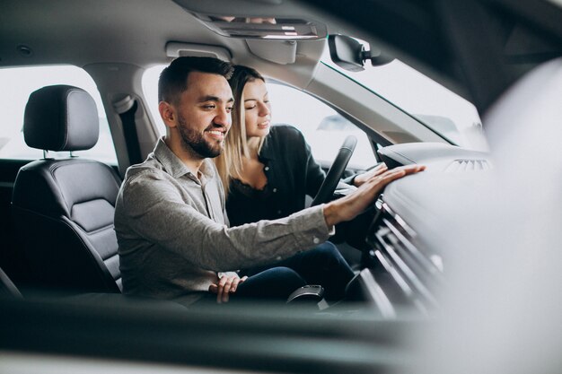 Pareja joven eligiendo un automóvil en una sala de exhibición de autos