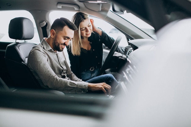 Foto gratuita pareja joven eligiendo un automóvil en una sala de exhibición de autos