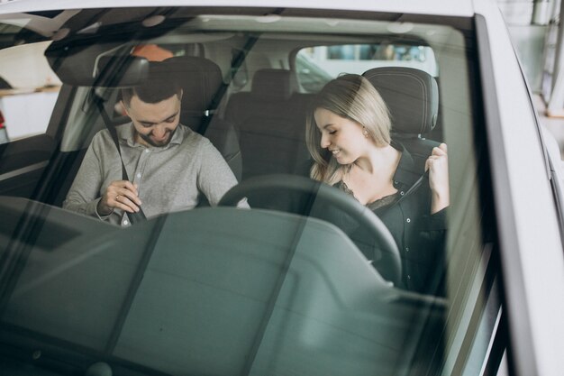 Pareja joven eligiendo un automóvil en una sala de exhibición de autos