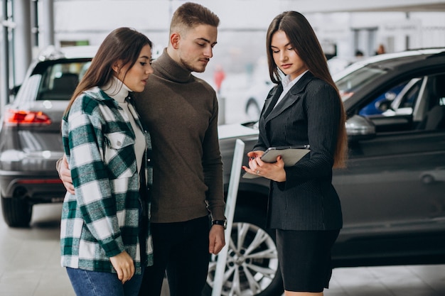 Pareja joven eligiendo un automóvil en una sala de exhibición de autos