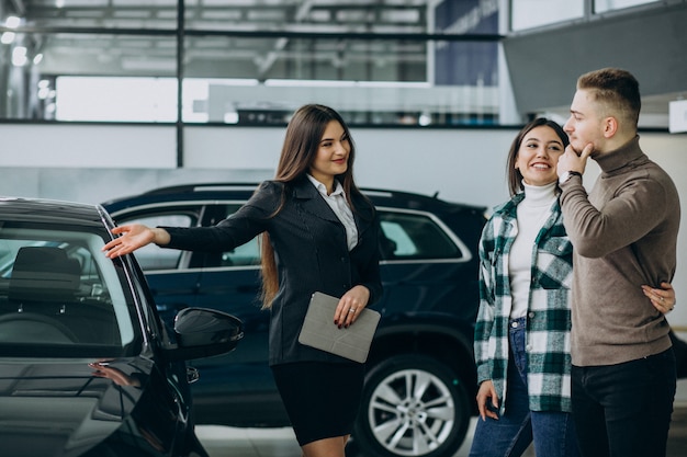 Pareja joven eligiendo un automóvil en una sala de exhibición de autos