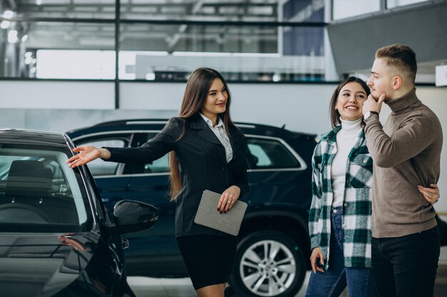 Pareja joven eligiendo un automóvil en una sala de exhibición de autos