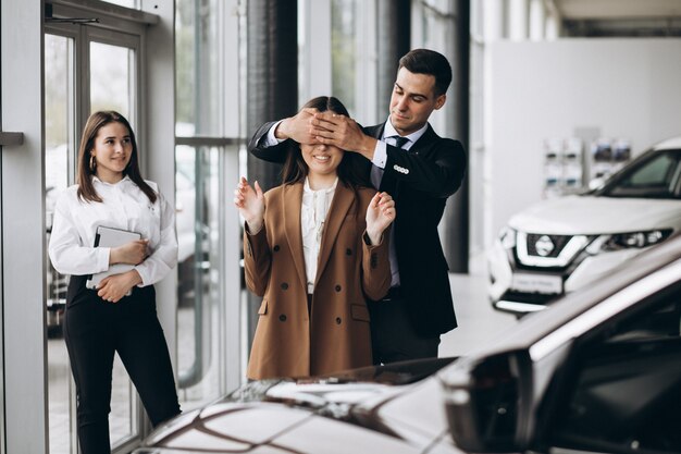 Pareja joven eligiendo un automóvil en una sala de exhibición de autos