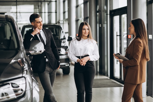 Pareja joven eligiendo un automóvil en una sala de exposición de automóviles