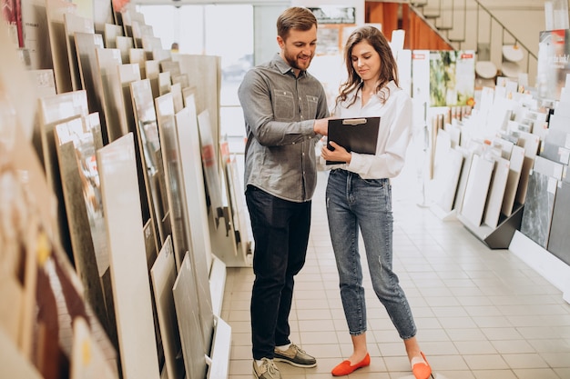 Pareja joven eligiendo azulejos en el mercado de la construcción