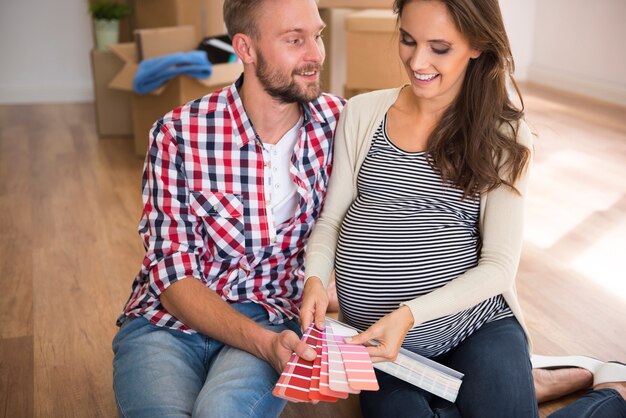 Pareja joven eligiendo el color para la habitación del bebé