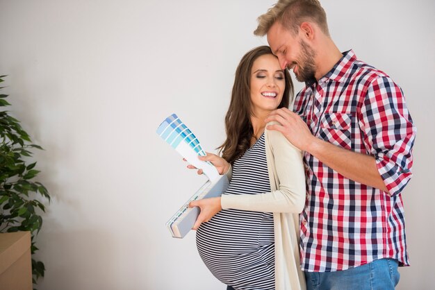 Foto gratuita pareja joven eligiendo el color para la habitación del bebé