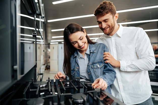 Foto gratuita pareja joven eligiendo nueva estufa de gas en la tienda de electrodomésticos