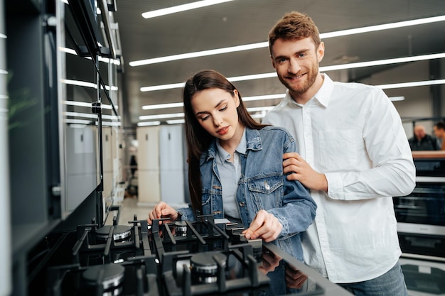 Pareja joven eligiendo nueva estufa de gas en la tienda de electrodomésticos