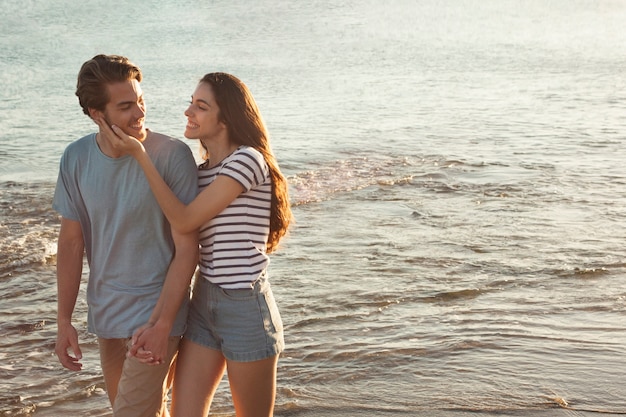 Pareja joven enamorada andando por la orilla