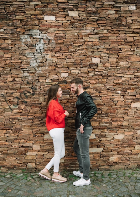 Pareja joven enamorada enfrente de muro de ladrillo