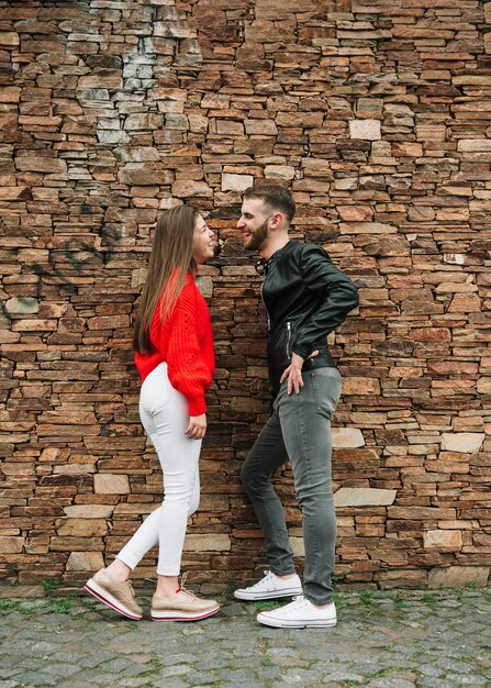 Pareja joven enamorada enfrente de muro de ladrillo