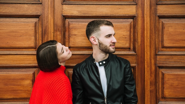 Pareja joven enamorada enfrente de puerta de madera