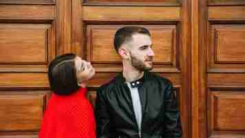 Foto gratuita pareja joven enamorada enfrente de puerta de madera