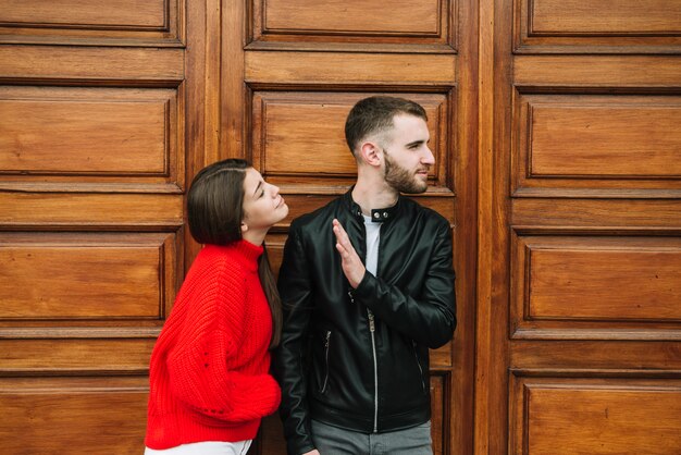 Pareja joven enamorada enfrente de puerta de madera