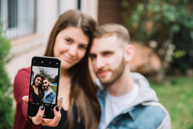 Pareja joven enamorada haciendo selfie en jardín